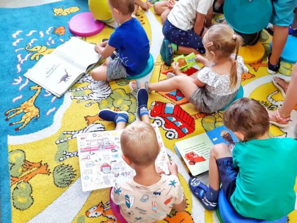 5 dzieci siedzi na dywanie i czyta ksiązki