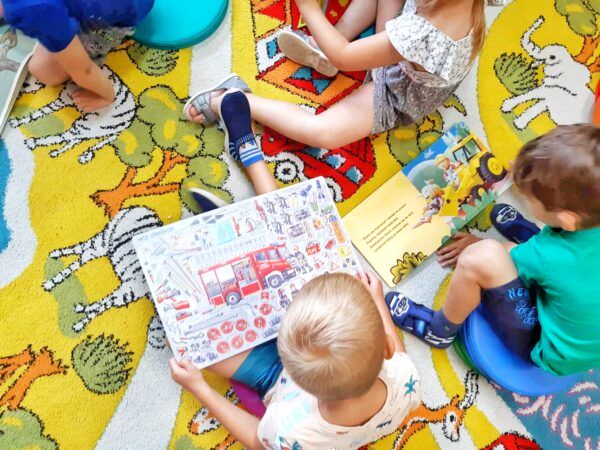 3 dzieci czyta książki na dywanie