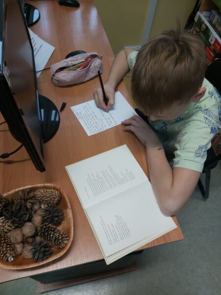 Chłopiec przepisujący wiersz przy biurku