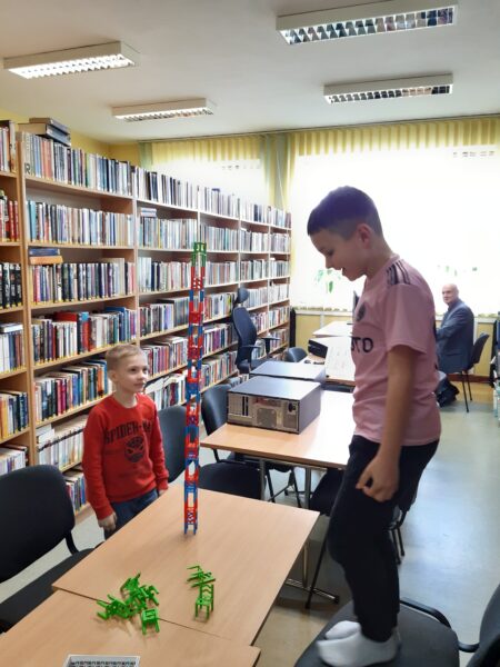 Chłopcy grają w bibliotece w planszówkę Mistakos - gra na stołki